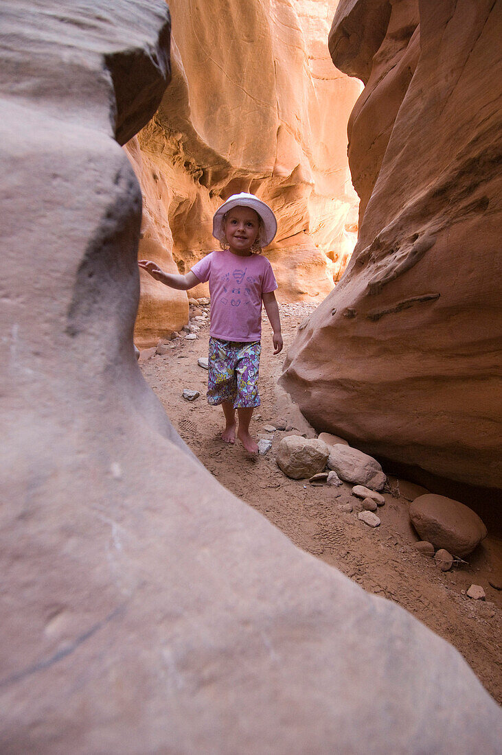 Young barefoot girl walking in sandstone slot canyon, Hanksville, Utah Hanksville, Utah, USA