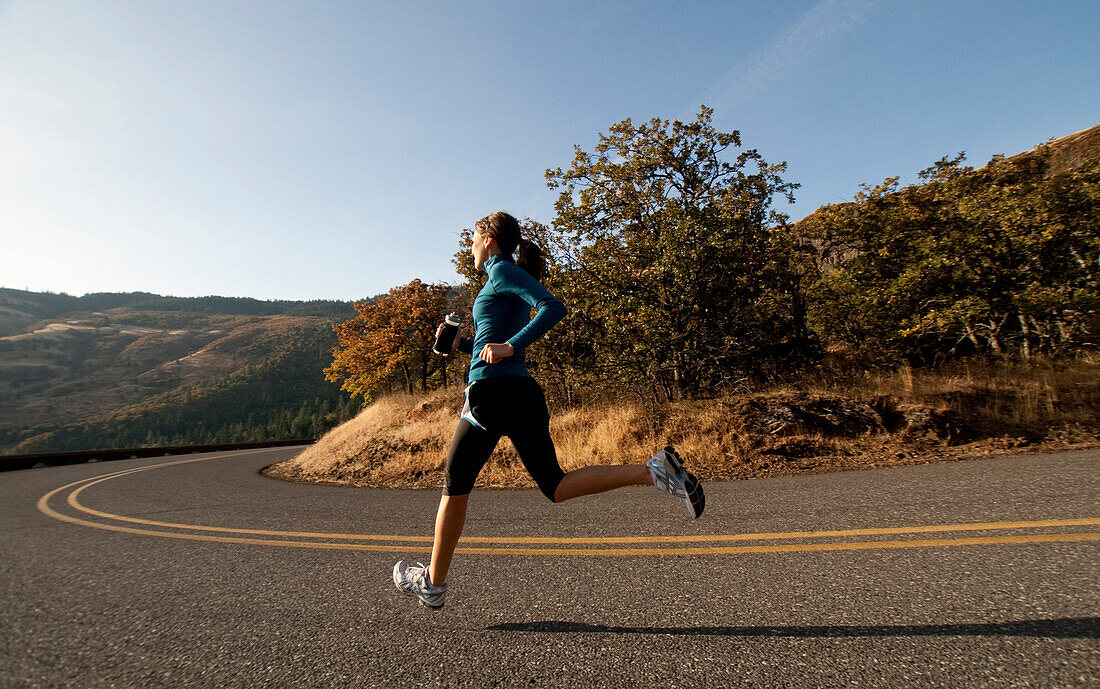 An athletic woman jogging in the Columbia Gorge, Oregon Hood River, Oregon, USA