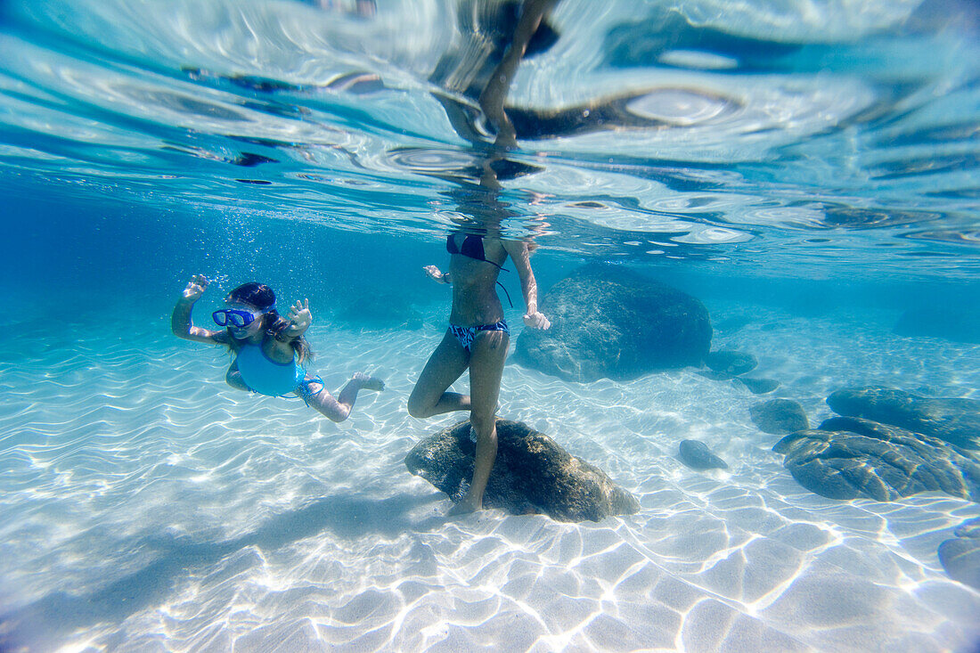 An underwater view of a  mother and daughter swimming at Waimea Bay in Hawaii north shore of Oahu, Hawaii, usa