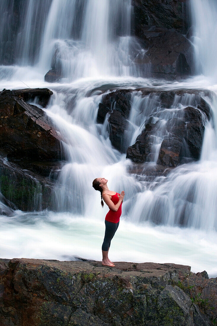 A woman performs yoga in front of a large waterfall in Lake Tahoe, California Lake Tahoe, California, USA