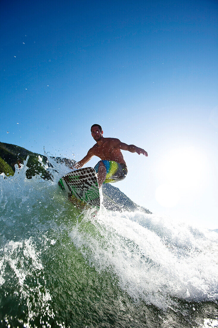 A athletic male surfing behind a wakeboard boat on a lake in Idaho Sandpoint, Idaho, USA