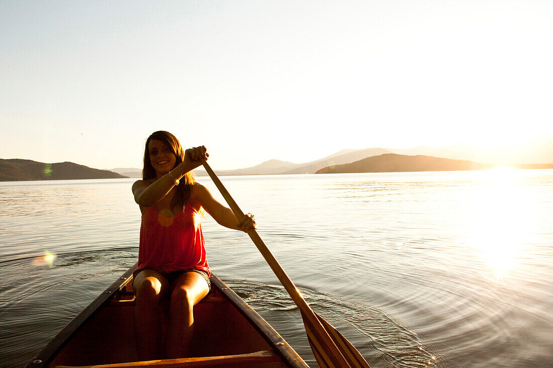 A happy young woman smiles while canoeing on a camping trip on a lake in Idaho Sandpoint, Idaho, USA