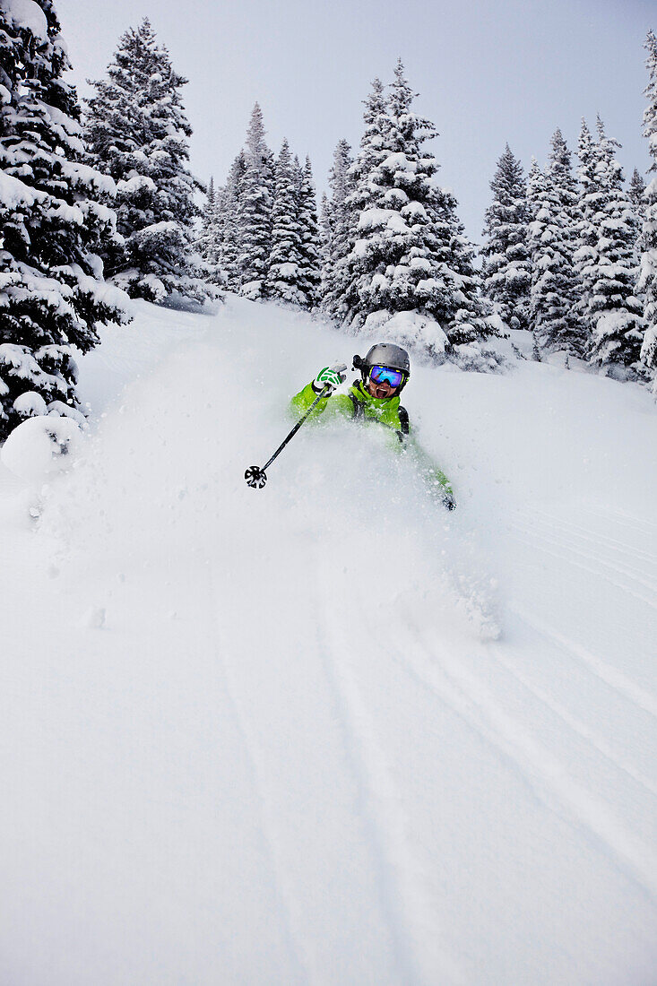 A athletic skier rips fresh deep powder turns in the backcountry on a stormy day in Colorado Vail, Colorado, USA