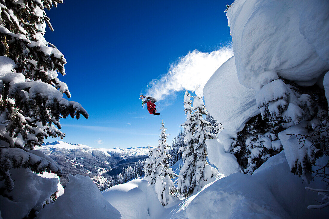 A athletic skier flipping off a cliff in the backcountry on a sunny powder day in Colorado Vail, Colorado, USA
