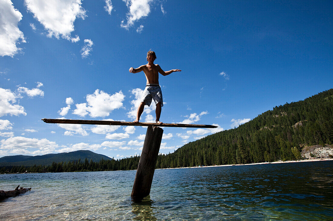 A young man balances on a teeter totters high above a lake in Idaho Priest Lake, Idaho, USA