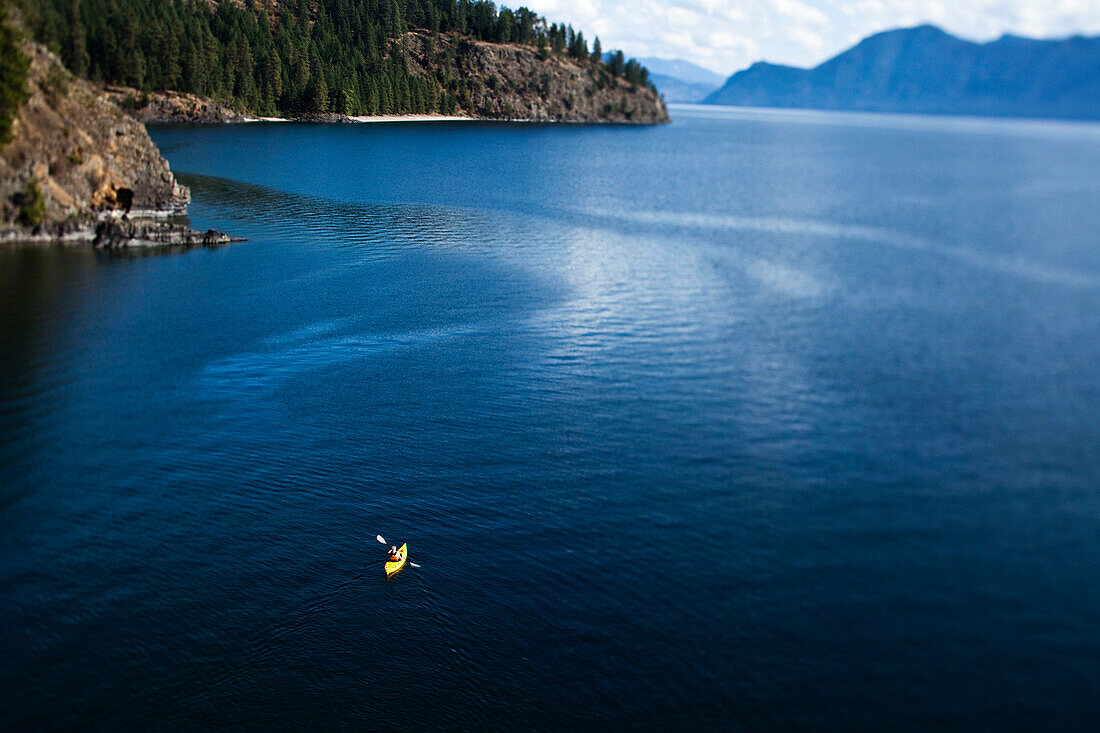 A athletic woman kayaking on a lake in Idaho., Sandpoint, Idaho, USA