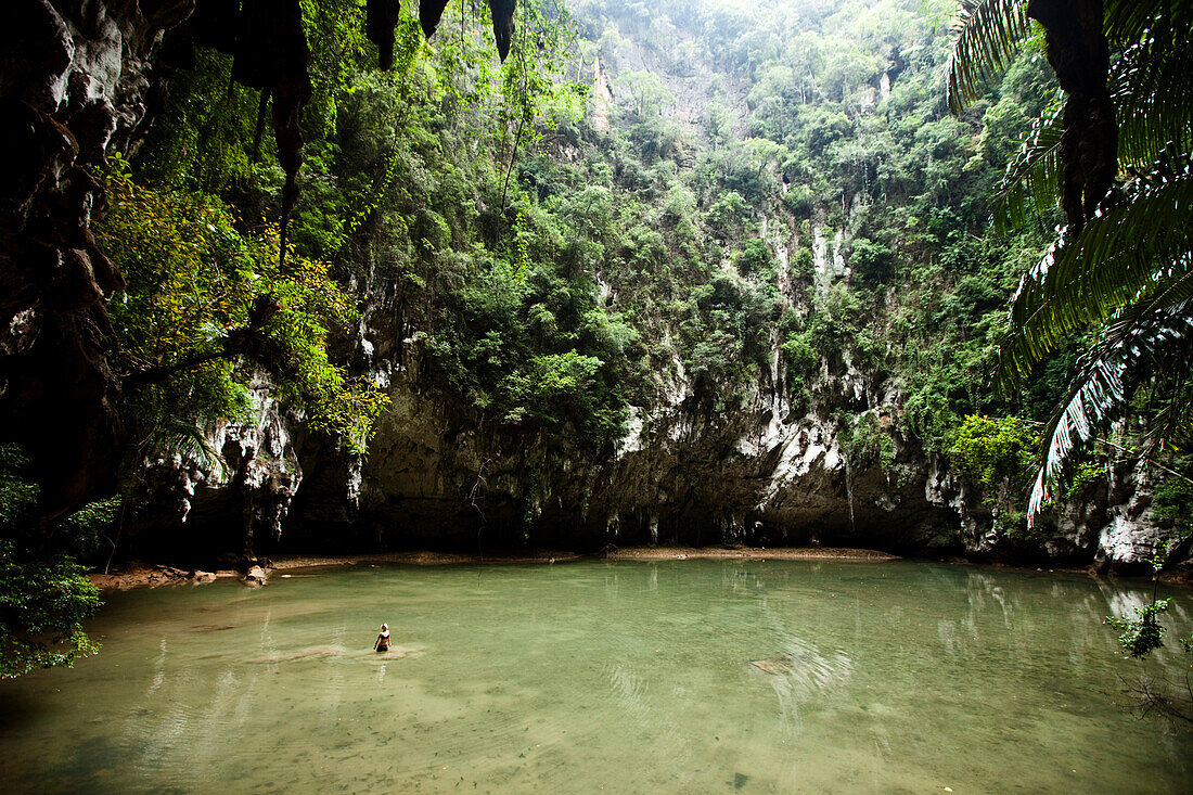 A beautiful young woman adventuring deep into a remote jungle pool relaxes in Thailand., Railay, Thailand