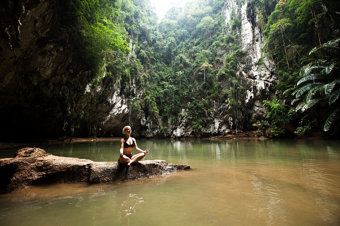 A beautiful young woman adventuring deep into a remote jungle pool relaxes in Thailand., Railay, Thailand