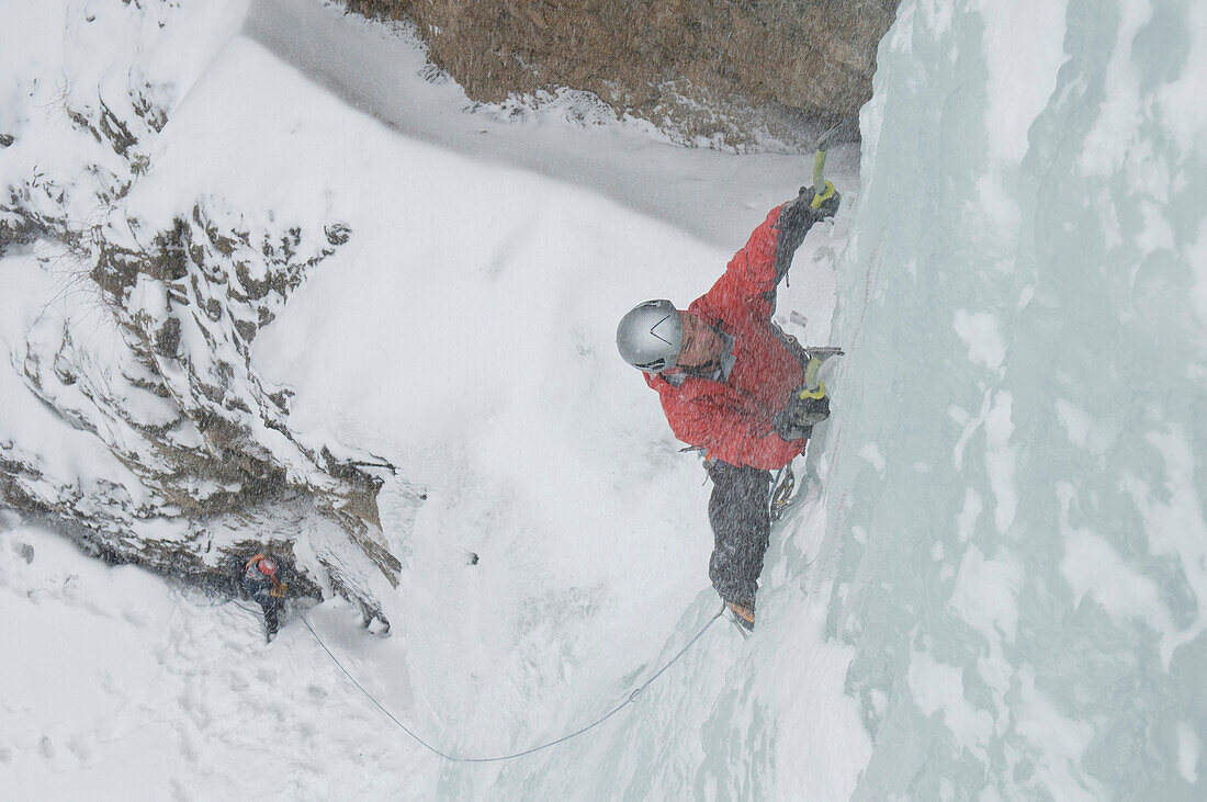 Two men ice climbing up Treasure Falls in a snowstorm, Pagosa Springs, Colorado., Pagosa Springs, Colorado, usa