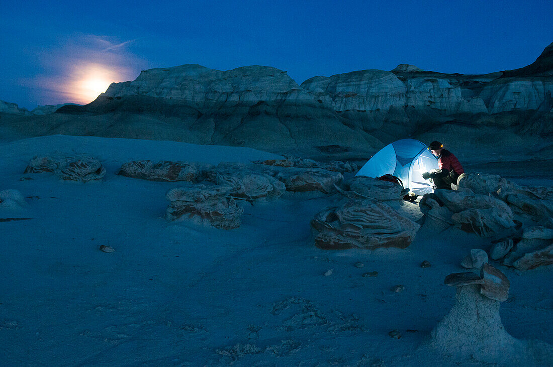 A man setting up a tent at night, Bisti Badlands, Farmington, New Mexico., Farmington, New Mexico, usa