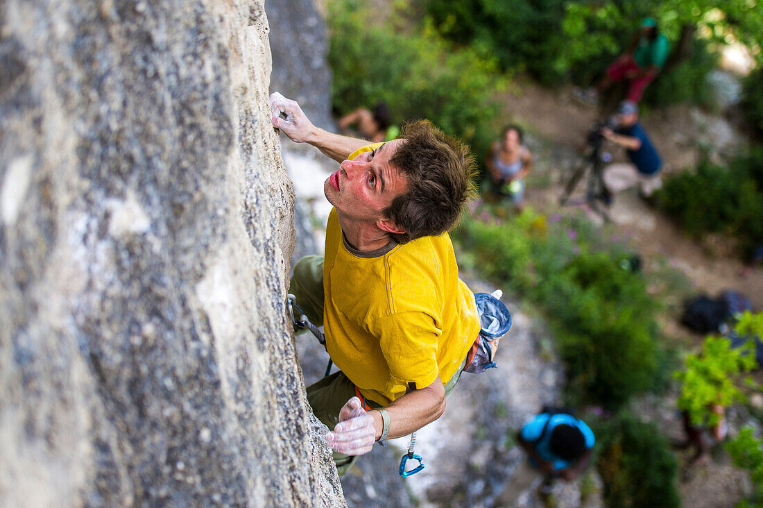 A top view on Gerome Pouvreau focusing on a difficult move while leading the climb on a limestone wall., Millau, France