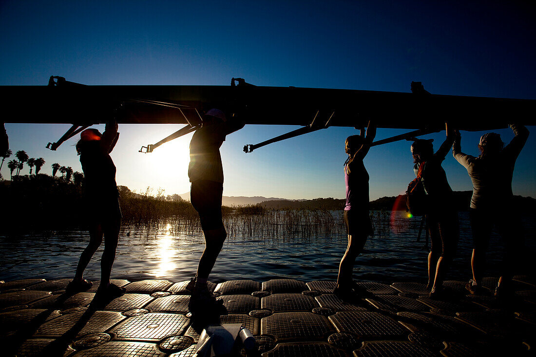 The Lake Casitas Rowing Team carries their boat down a dock at Lake Casitas in Ojai California., Ojai, California, United States of America
