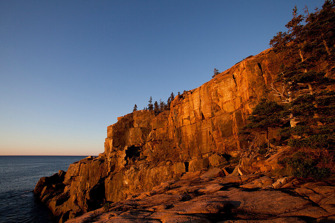 The first rays of sunshine light up the Otter Cliffs located in Acadia National Park near Bar Harbor, Maine., Bar Harbor, Maine, USA