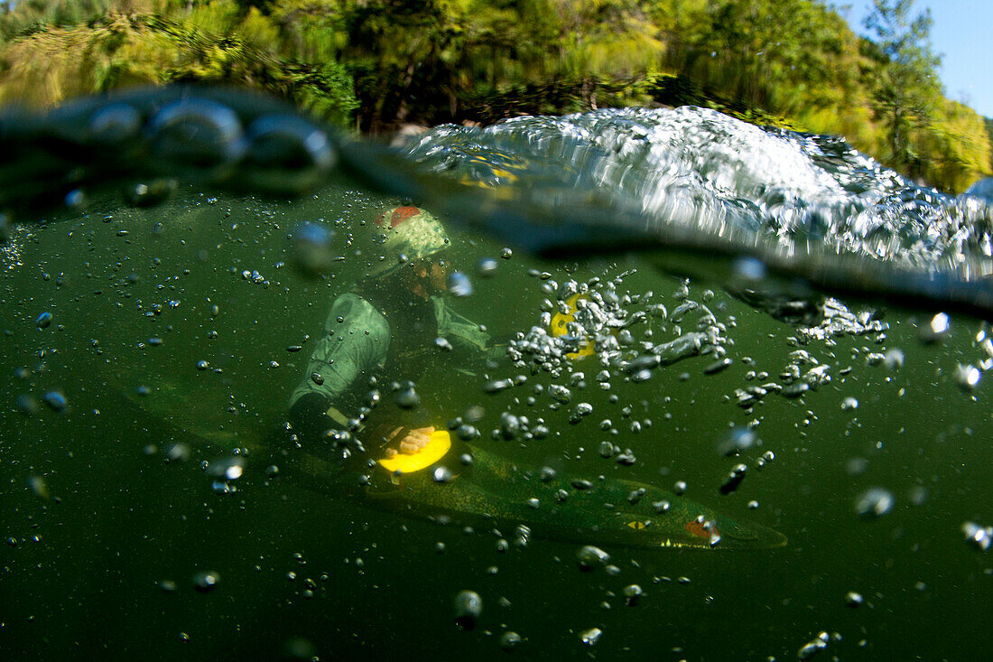 Split level view of one man squirtboating / kayaking underwater with bubbles., Fayetteville, WV, USA