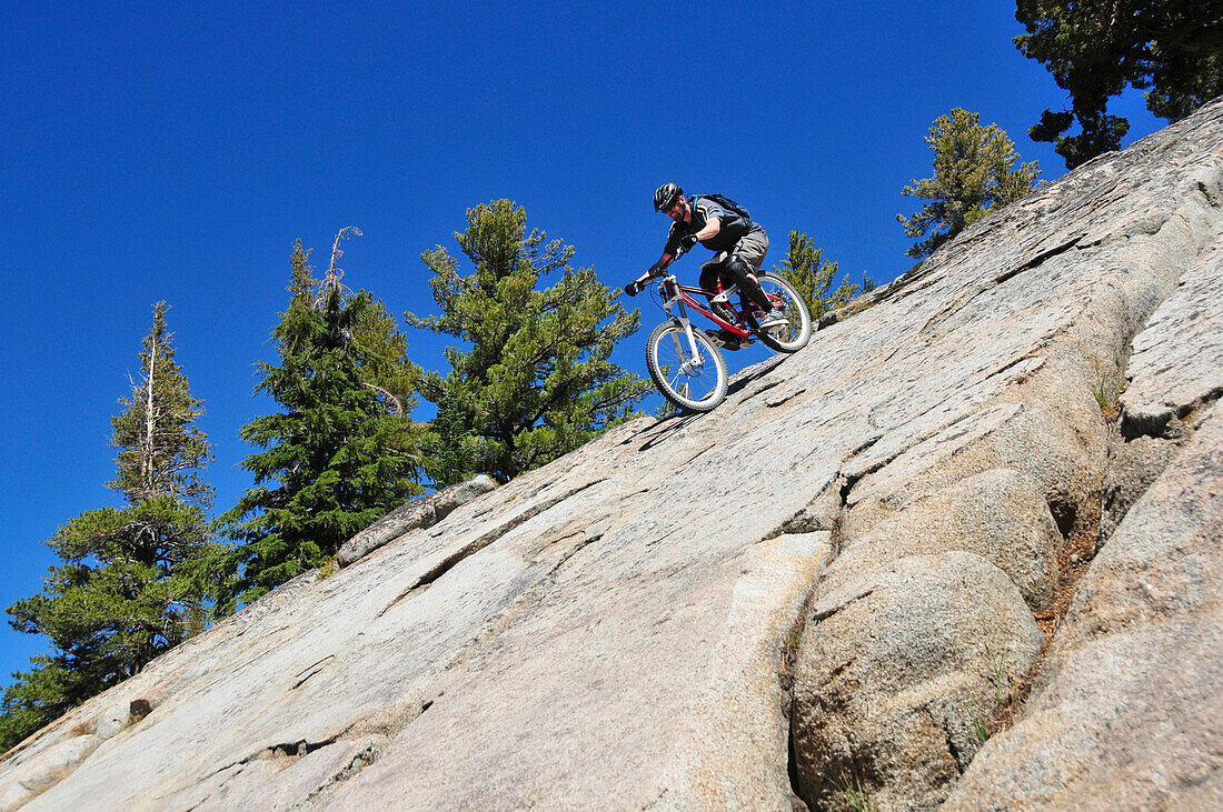 A mountain biker rides down an extremely steep slab of granite at Kirkwood Mountain Resort, CA., Kirkwood, California, USA