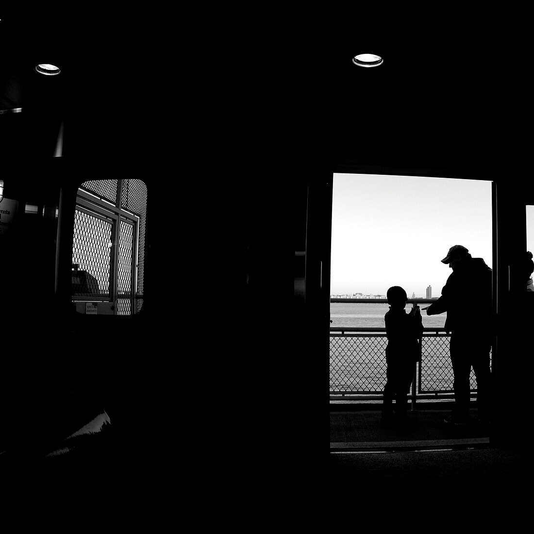 Silouhette of a man & a boy on the ferry in NYC., New York City, NY, USA