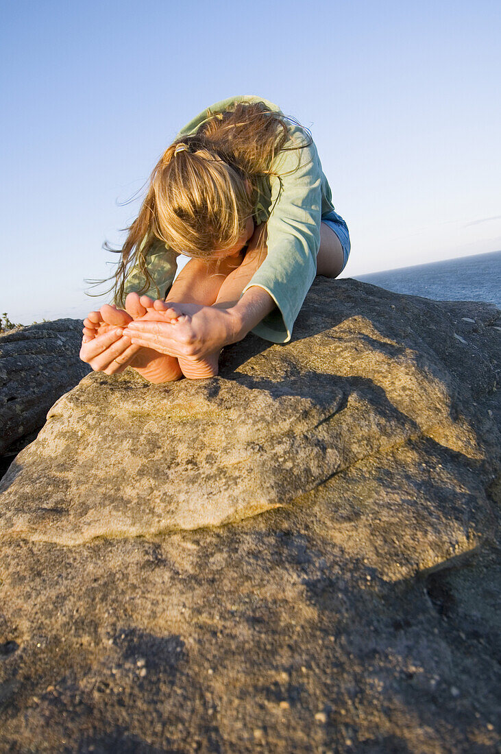 Yoga on rocky outcrop above ocean Sydney, New South Wales, Australia