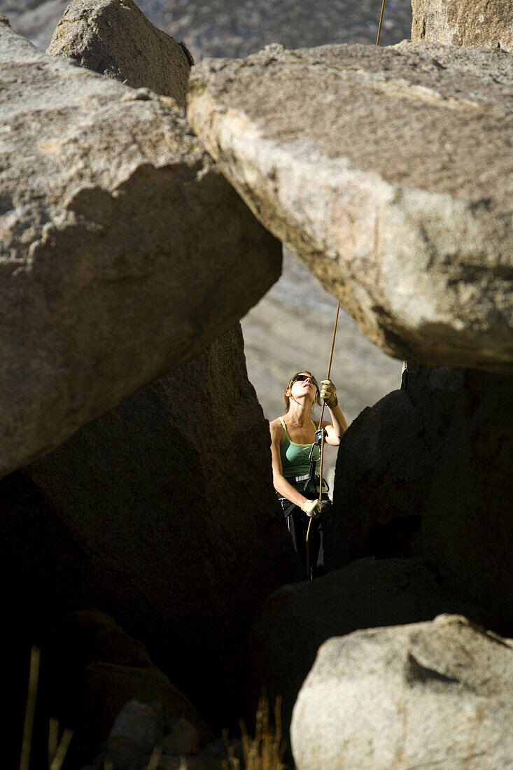 Female belaying between rocks, Bishop, California, United States