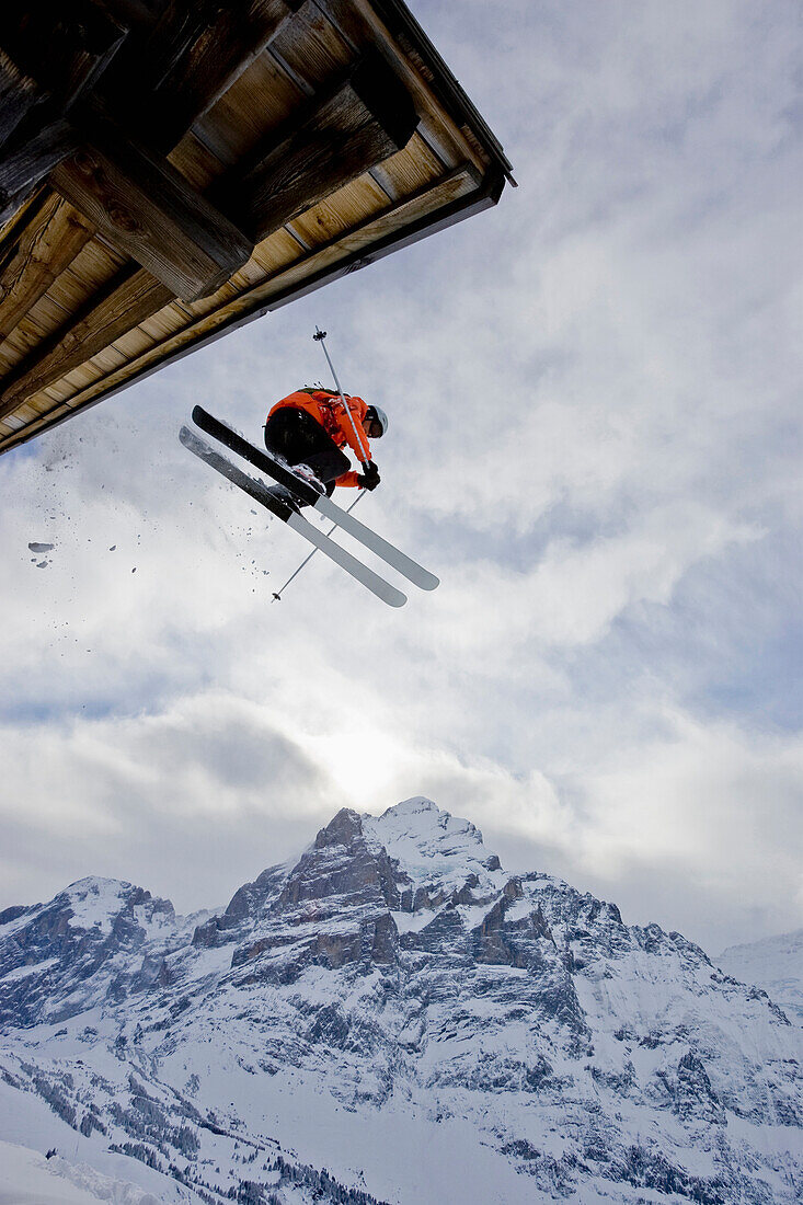 A young man skis off the roof of an alpine hut in Grindalwald, Switzerland Grindelwald, Jungfrau region, Switzerland