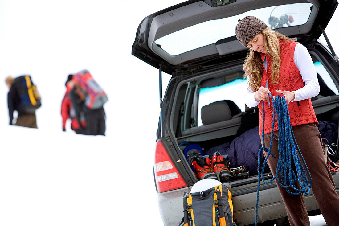 A woman preparing to go ice climbing and arranging gear from her trunk Mount Hood, Oregon, USA