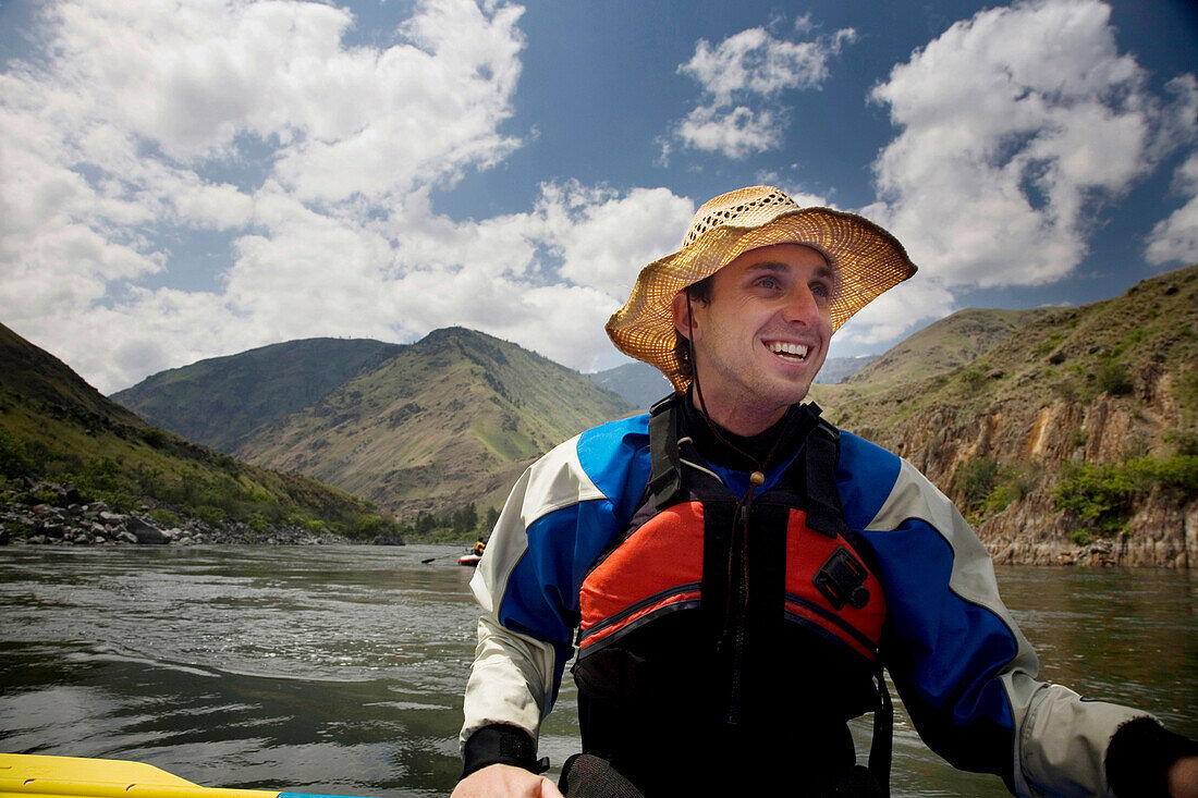 A smiling man floats on a raft down a river in Idaho, USA Idaho, USA