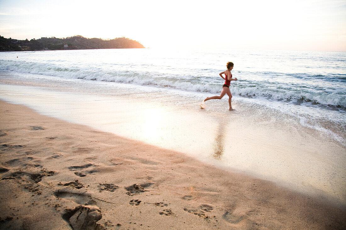 A young woman runs in the surf at sunset in Sayulita, Mexico Sayulita, Jalisco, Mexico