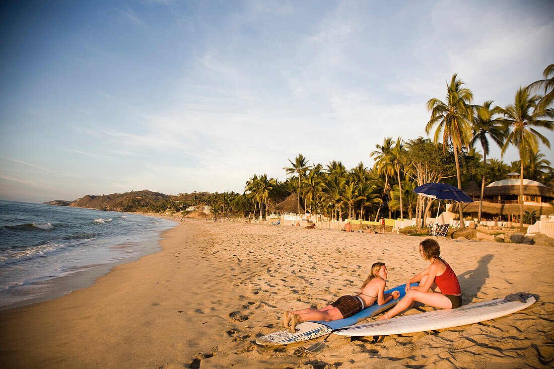 Two young girls sit on their surfboards after surfing near a remote beach in Sayulita, Mexico Sayulita, Jalisco, Mexico
