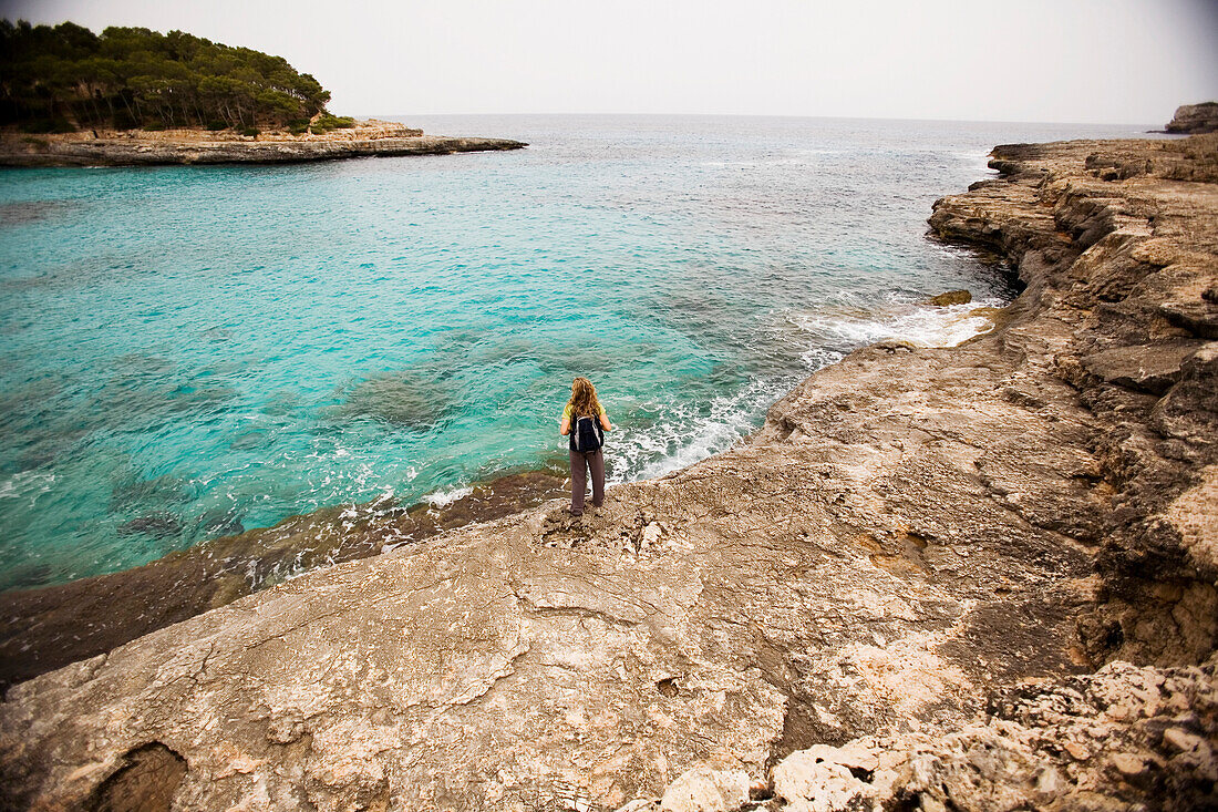 A woman walks along the coastline while on vacation Mallorca, Spain