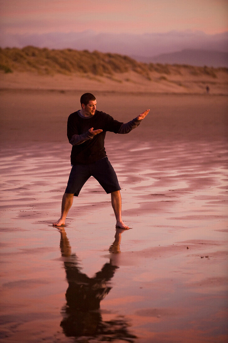 One mid adult man practices Taekwondo on the beach at sunset in Morro Bay, California Morro Bay, California, USA
