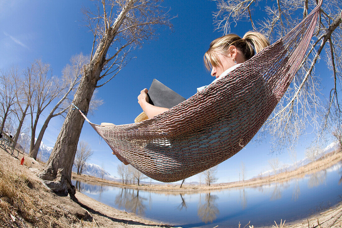 Young woman writing in journal while resting in hammock in Bishop, CA Bishop, California, USA