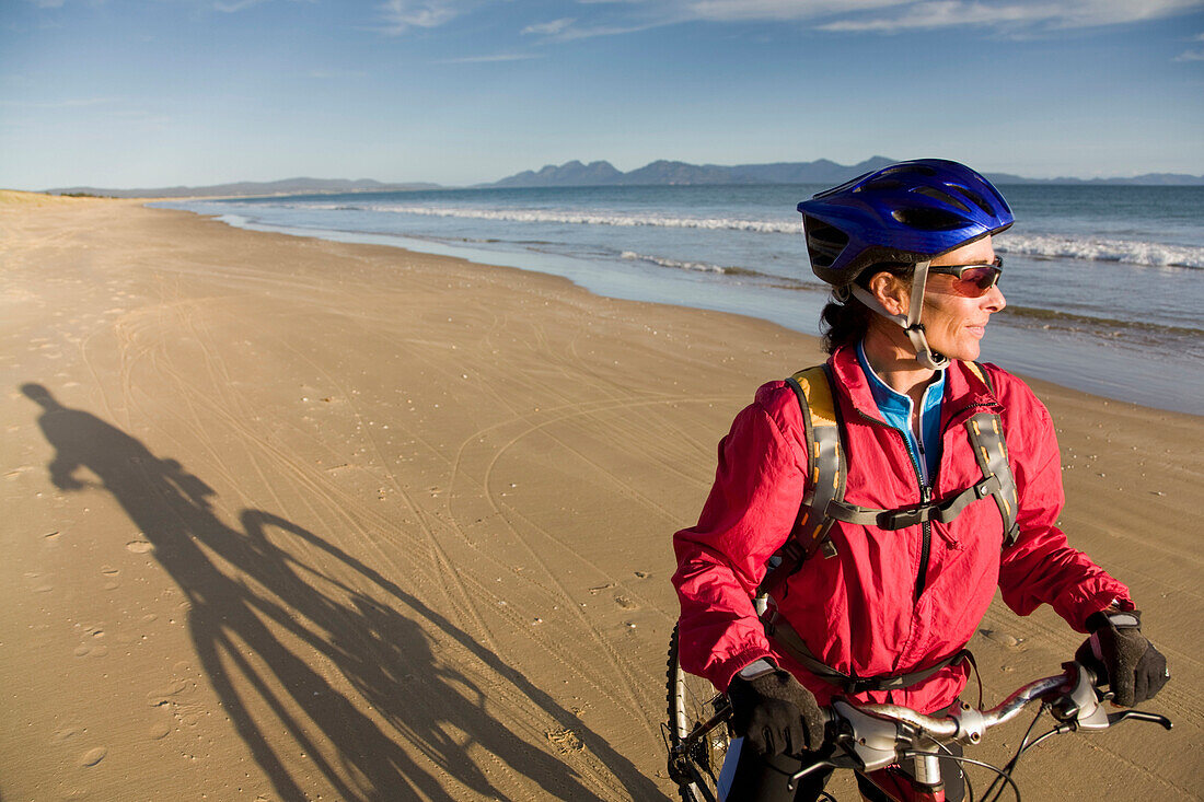 A woman enjoying a bike ride on Nine Mile Beach on the east coast of Tasmania, Australia Tasmania, Australia