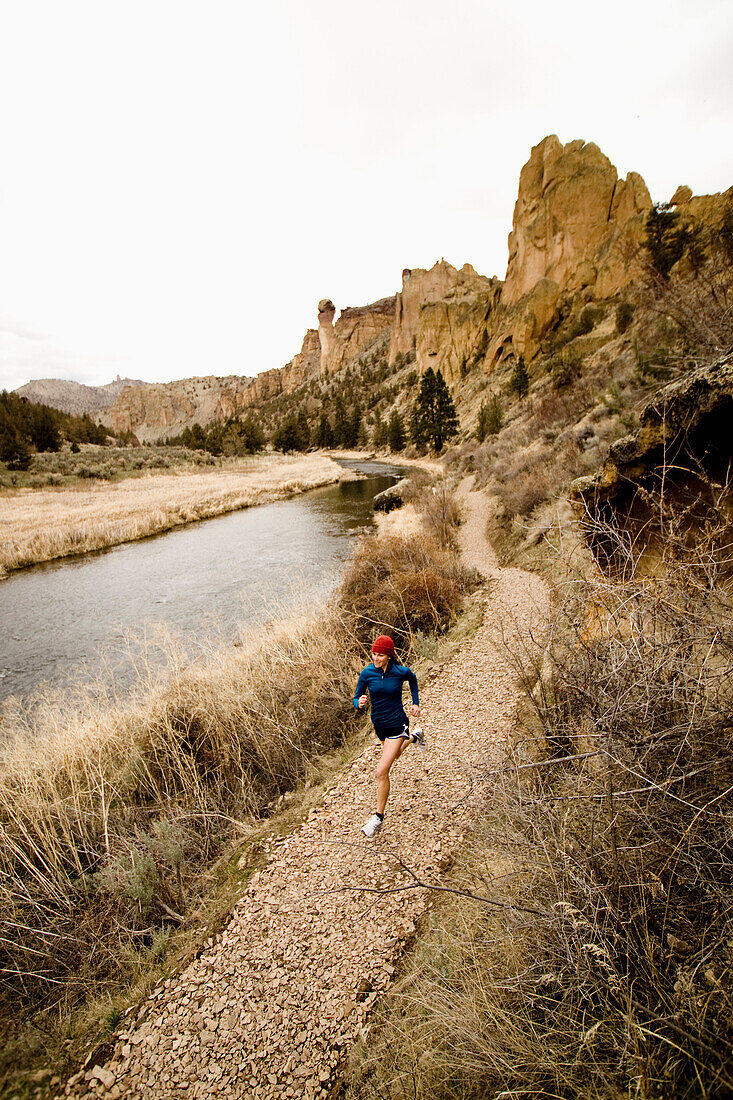 A woman in bright colors jogging near a river Terrebone, Oregon, USA