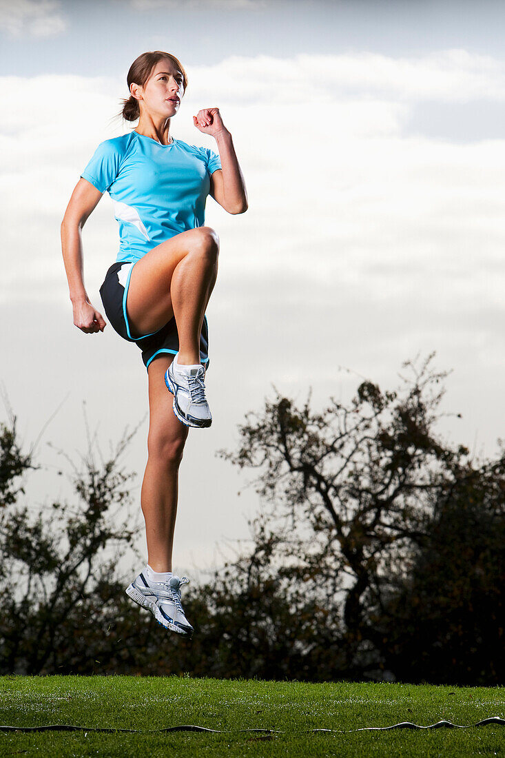 An athletic woman jumping in the air to prepare for a run in San Diego, California San Diego, California, USA