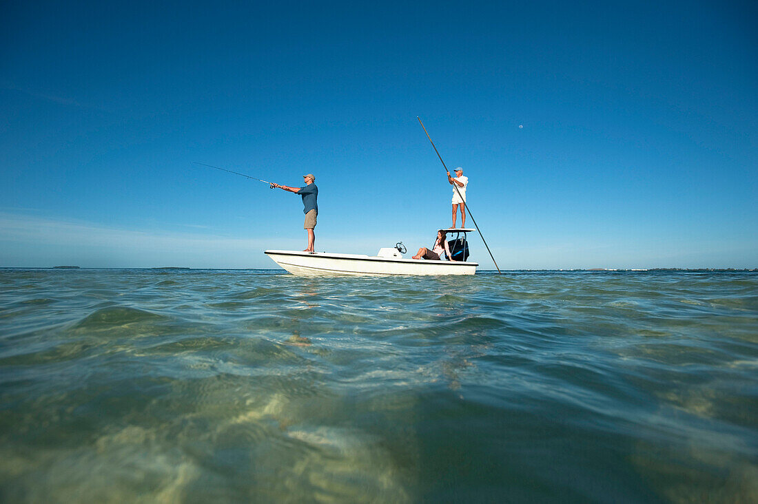 A couple fish as a man pilots a small boat in Florida Key West, Florida, USA