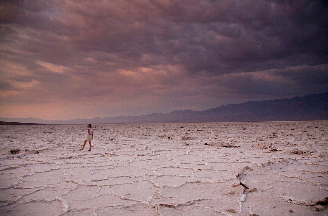 A woman standing under sunrise clouds in Death Valley National Park, California Death Valley National Park, California, USA