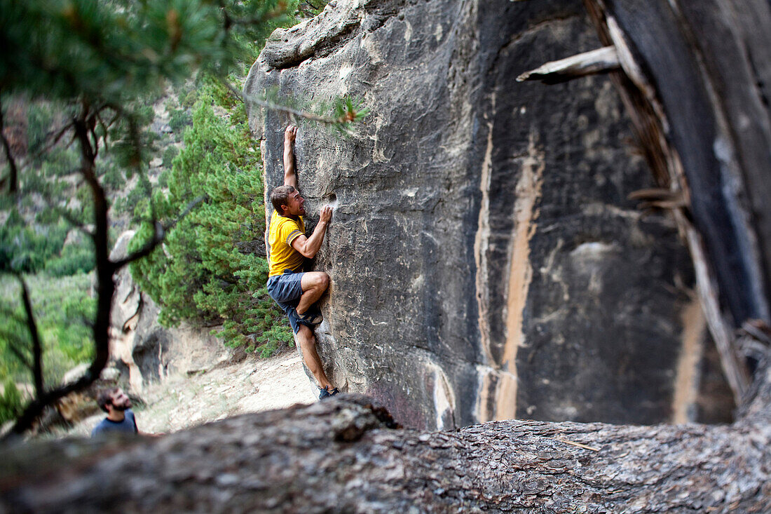 A man pulls hard while looking for his next hold on a boulder problem in Joes Valley, Utah Colorado, USA