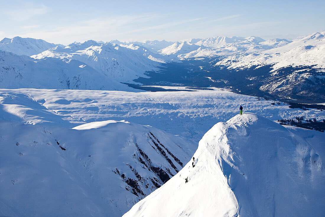 A male skier stands alone on top of a big, remote mountain in Haines, Alaska Haines, Alaska, USA