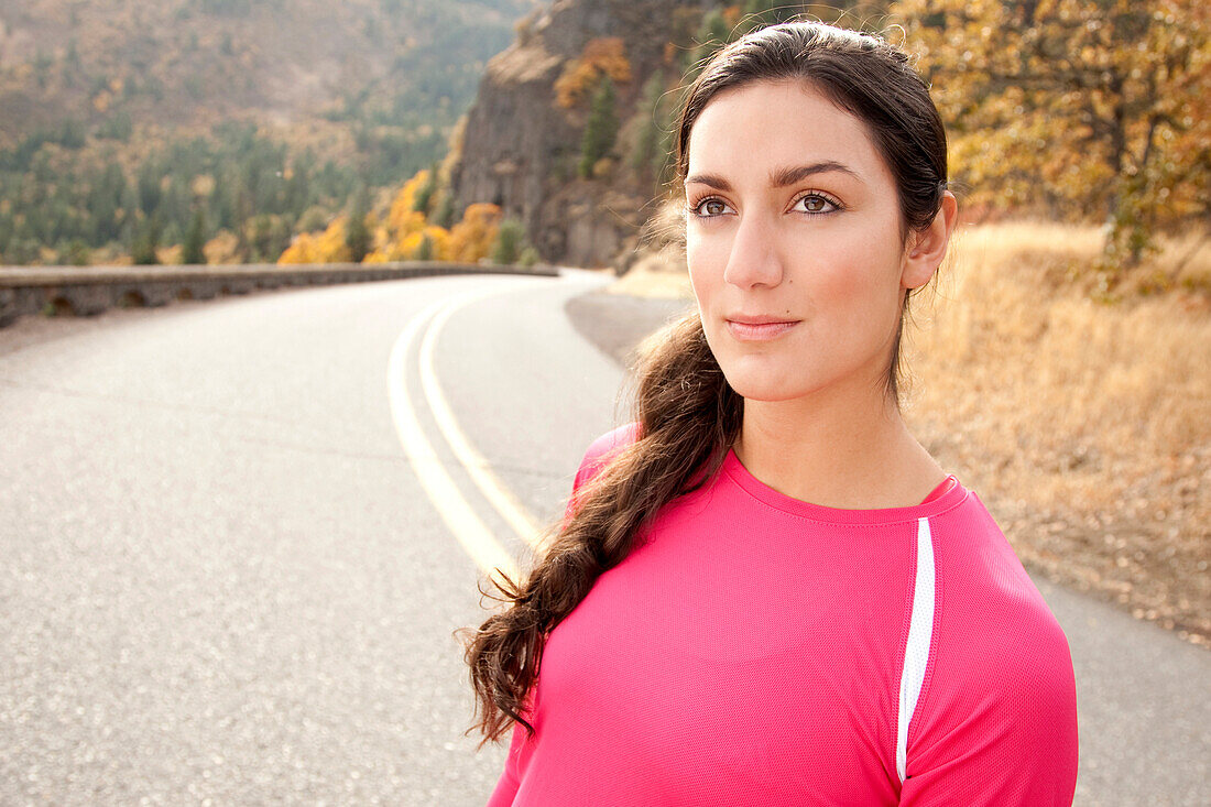 An athletic female standing along a historic highway on a fall day Hood River, Oregon, USA