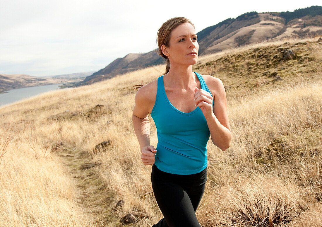 An athletic female jogs on a  dirt trail on an autumn day Hood River, Oregon, USA