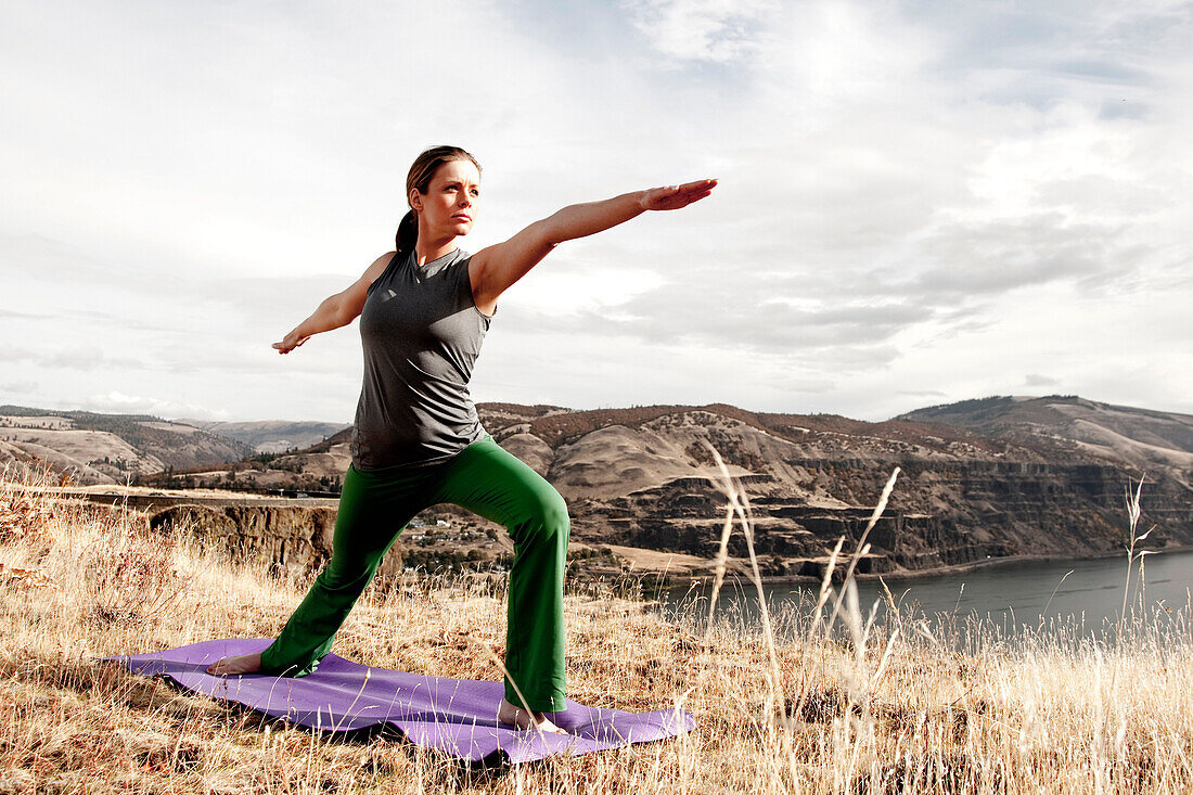 A female practicing yoga in the outdoors with the Columbia River Gorge in the distance Hood River, Oregon, USA