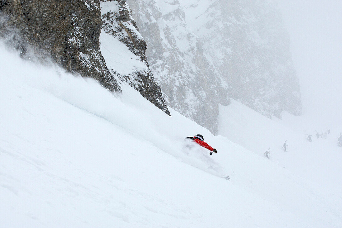 A man skiing beneath a cliff in Jackson Hole, Wyoming Jackson, Wyoming, USA