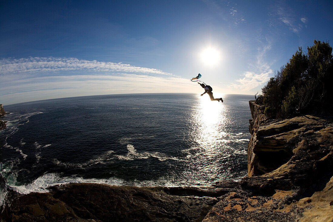 A BASE jumper leaps off a cliff over the ocean in Sydney, New South Wales, Australia Sydney, New South Wales, Australia