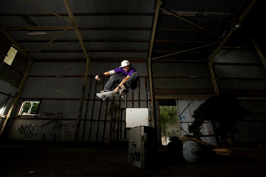 A skater performs a grab at an abandoned warehouse on the Central Coast, New South Wales, Australia Central Coast, New South Wales, Australia