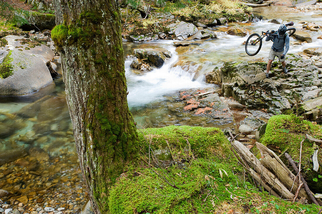 A mountain biker forges a small river in northern Idaho Idaho, USA