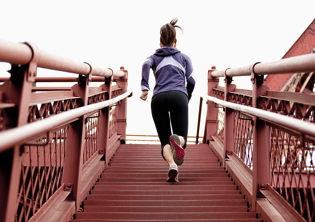 An athletic female in a purple jacket running stairs in Portland, Oregon Portland, Oregon, USA
