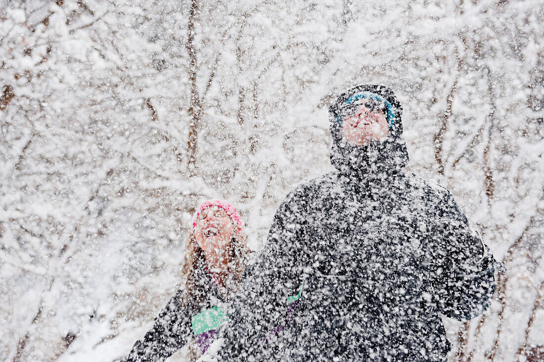 A young couple enjoys the falling snow in Milcreek Canyon, Salt Lake City, Utah Salt Lake City, Utah, USA
