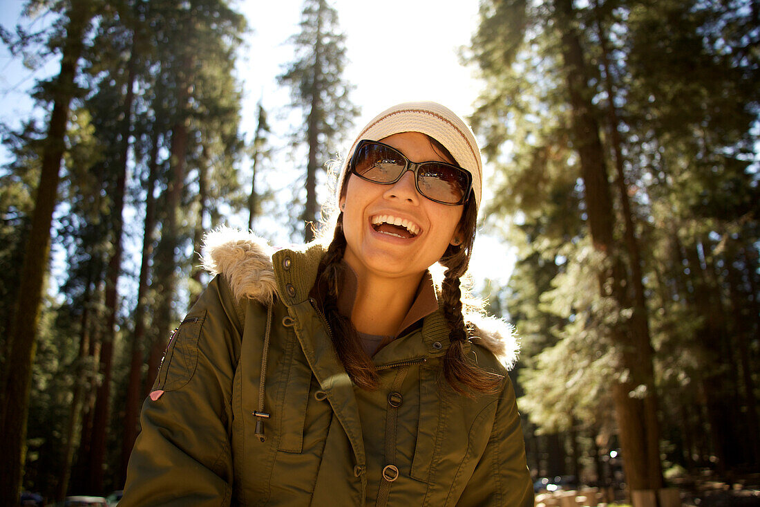 Woman in sunglasses looks down at the camera after hiking Yosemite National Park, California and laughs Yosemite National Park, California, USA