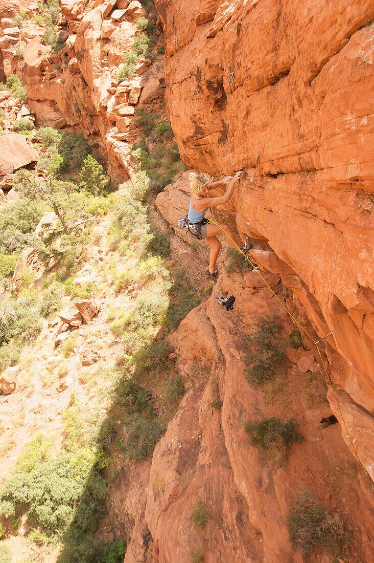 A rock climber ascends a red rock face in Nevada Las Vegas, Nevada, USA