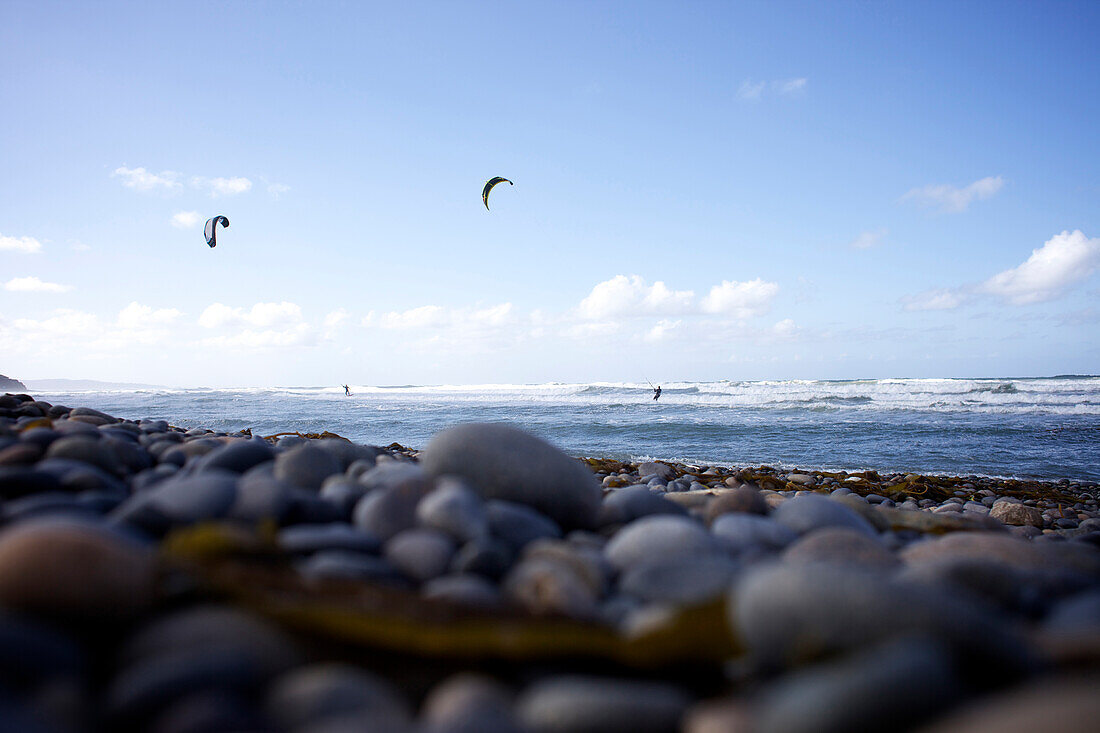 Two male kitesurfers riding the waves from a rocky beach Cardiff-by-the-sea, California, USA