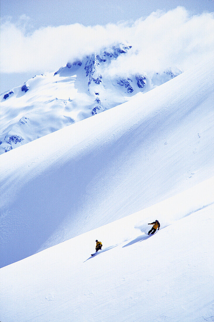 Two snowboarders on an empty mountain making turns Whistler, British Columbia, Canada